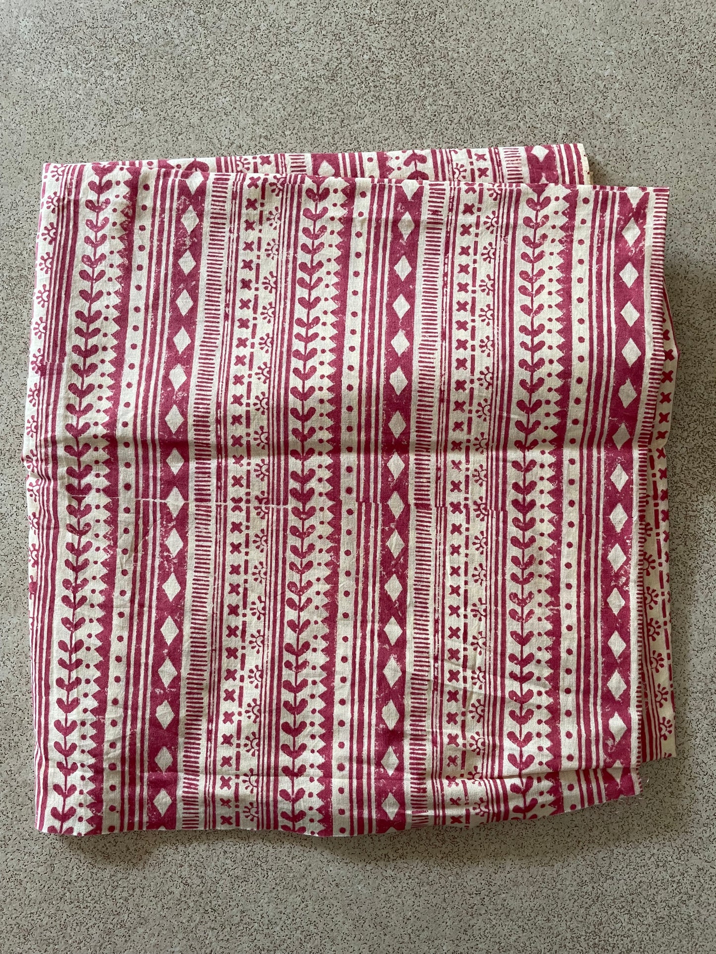 Folded Mogasu saree blouse piece with a red and cream pattern on a gray surface.