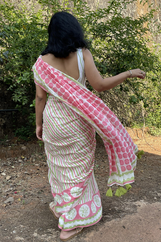 Woman in a Mogasu pink and white mul cotton saree with green star fruit patterns walking outdoors in Goa.