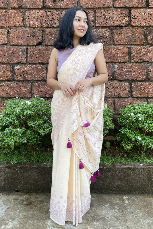 Woman in a Mogasu cream saree with pink blouse standing against a brick wall in Goa.