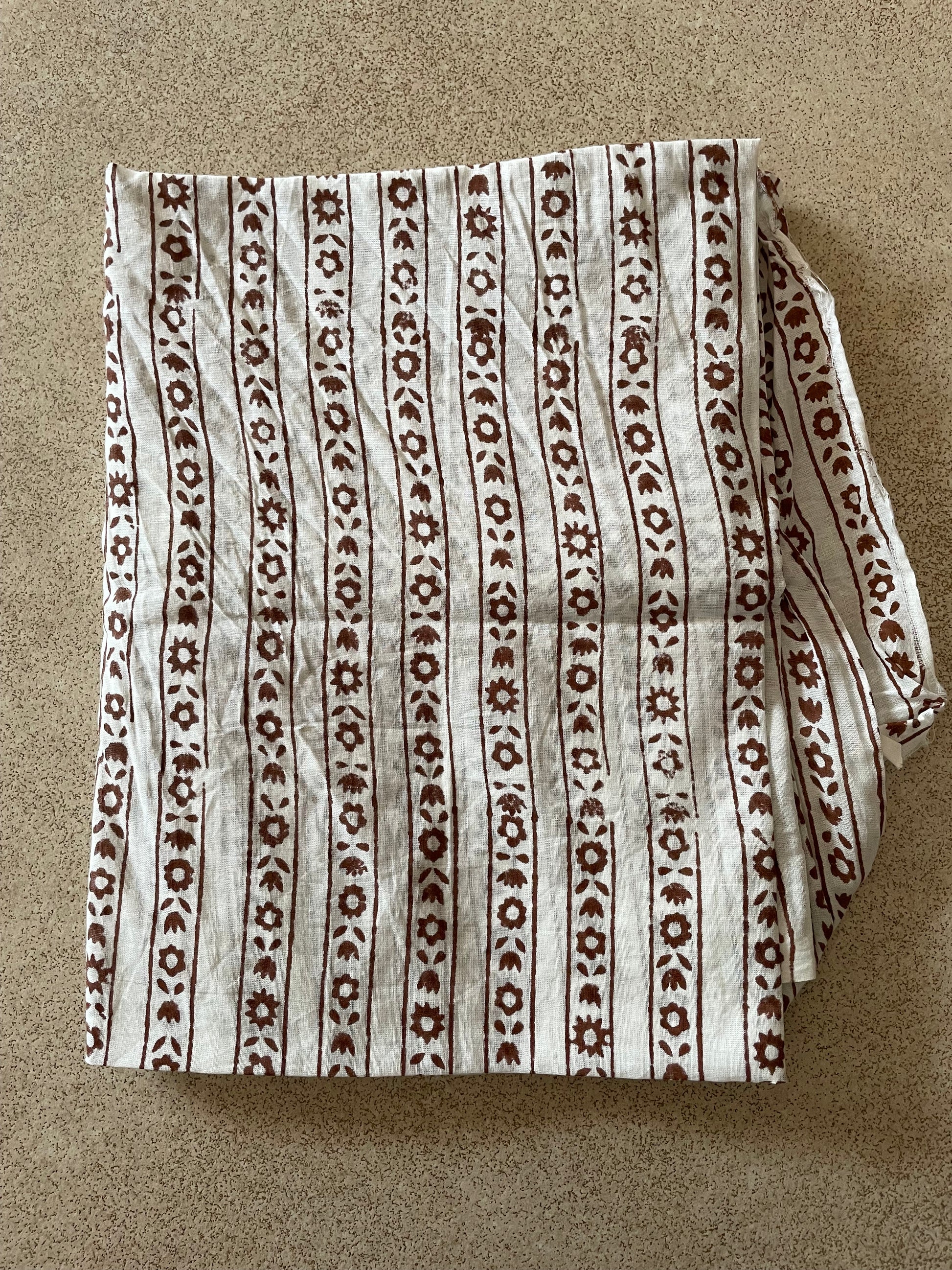 Folded Mogasu blouse piece with a brown pattern on a beige background