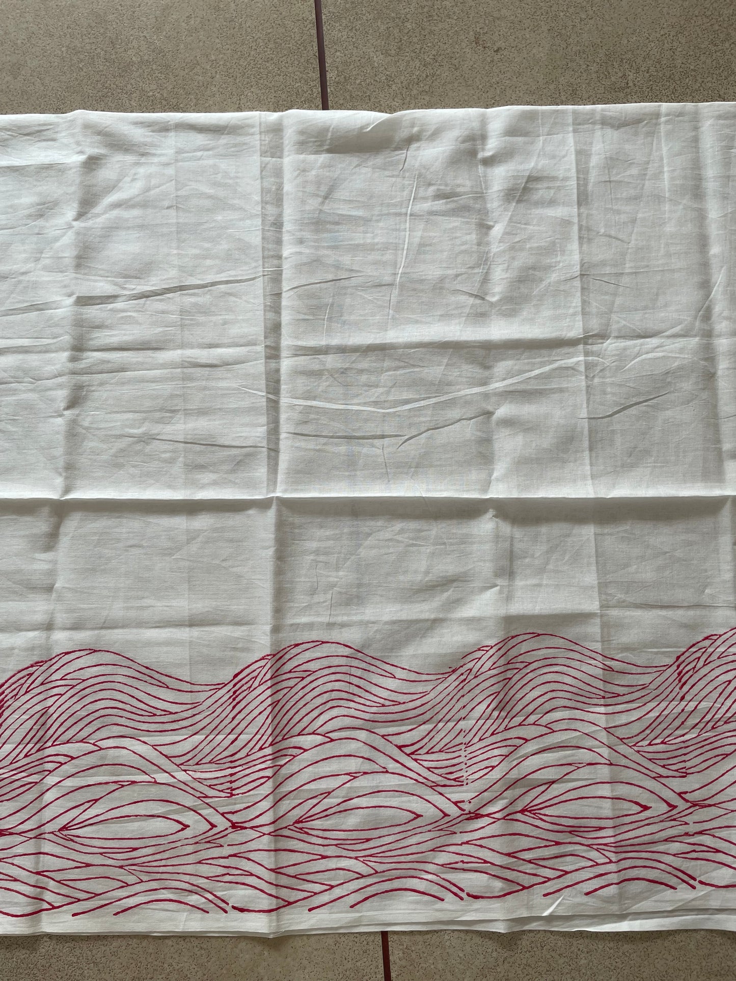 White Mogasu saree blouse piece with red wavy pattern on a beige surface.