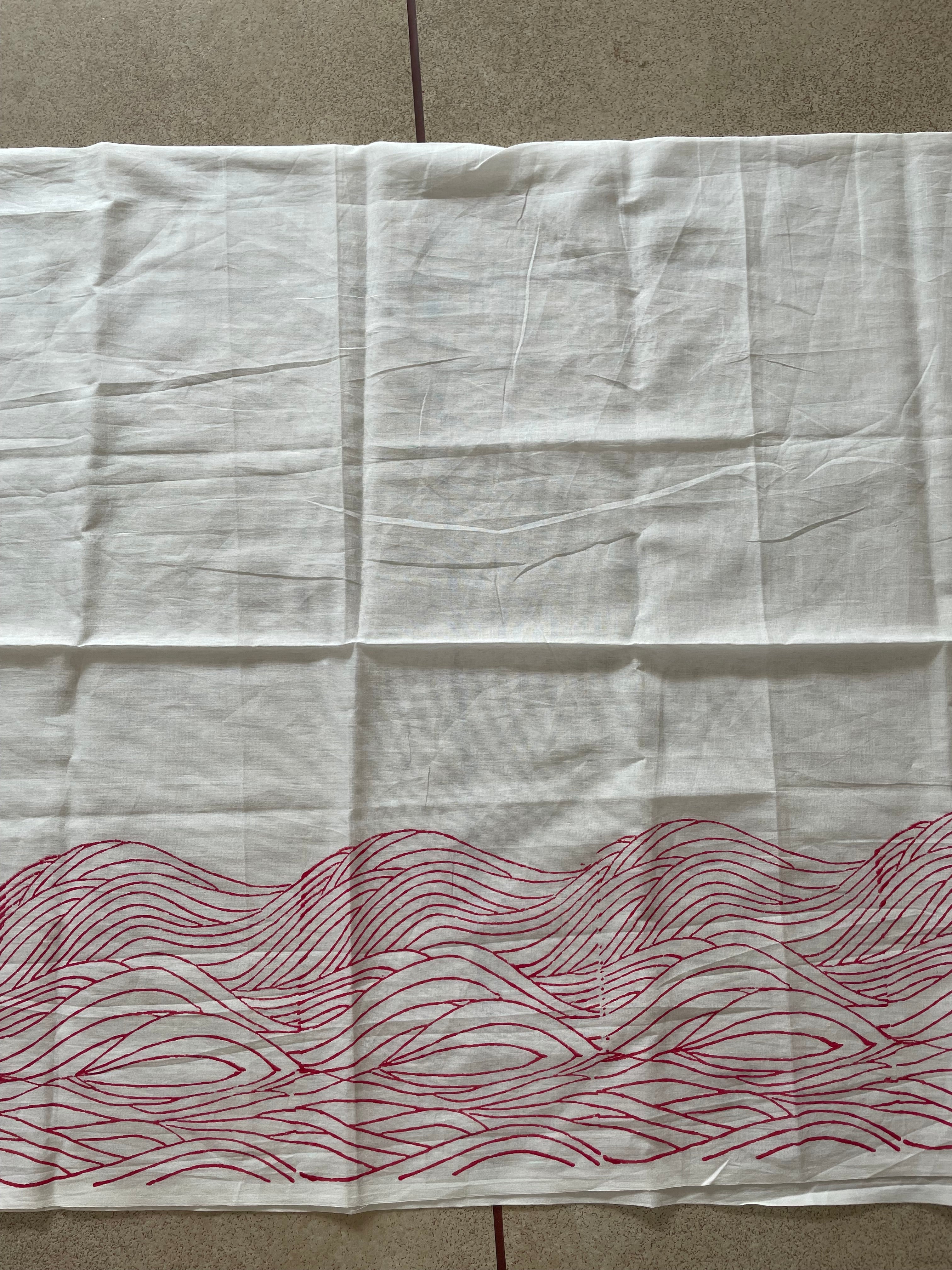 White Mogasu saree blouse piece with red wavy pattern on a beige surface.