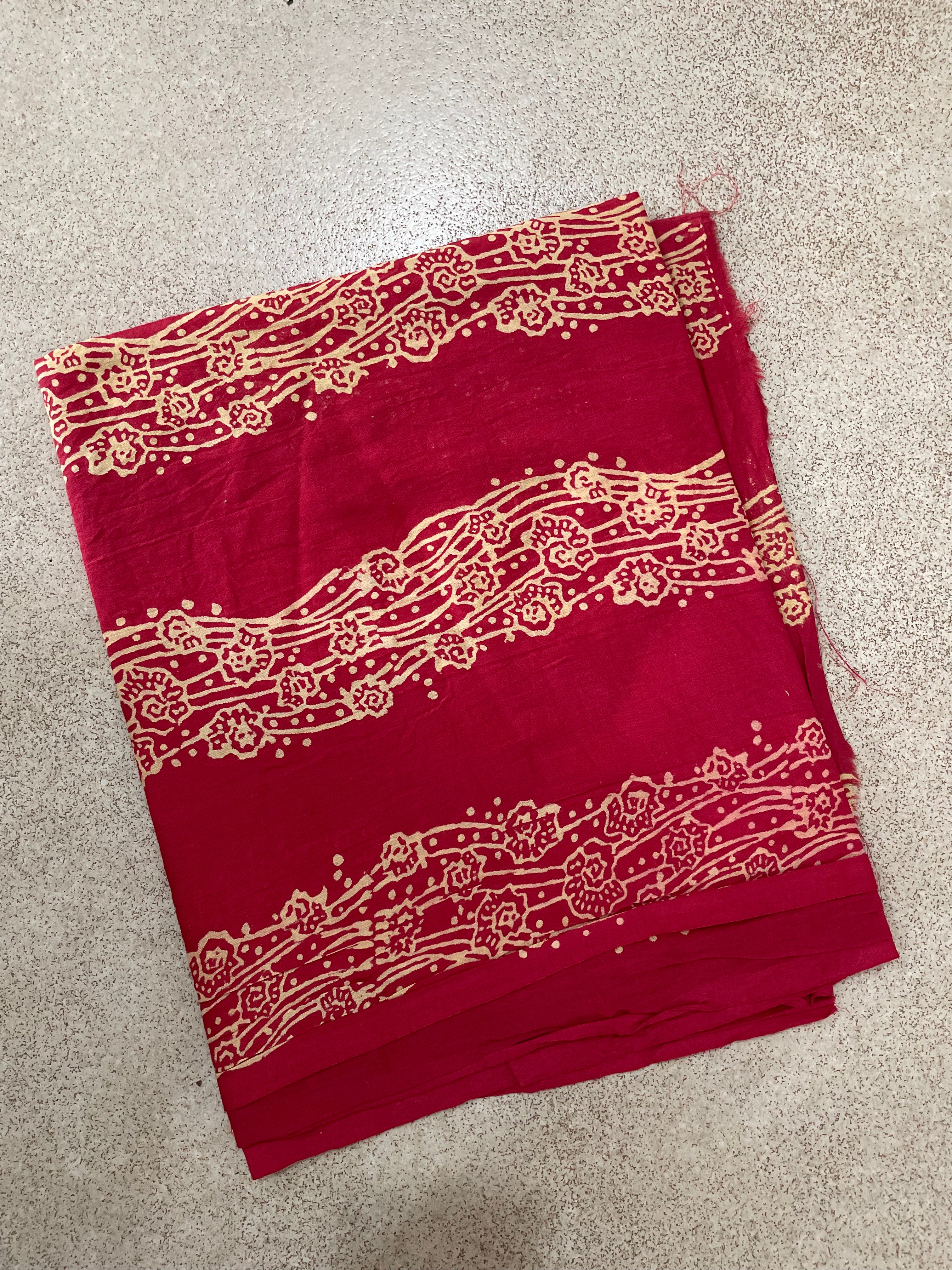 Red Mogasu Lhaar saree blouse piece fabric with yellow block print on a beige surface