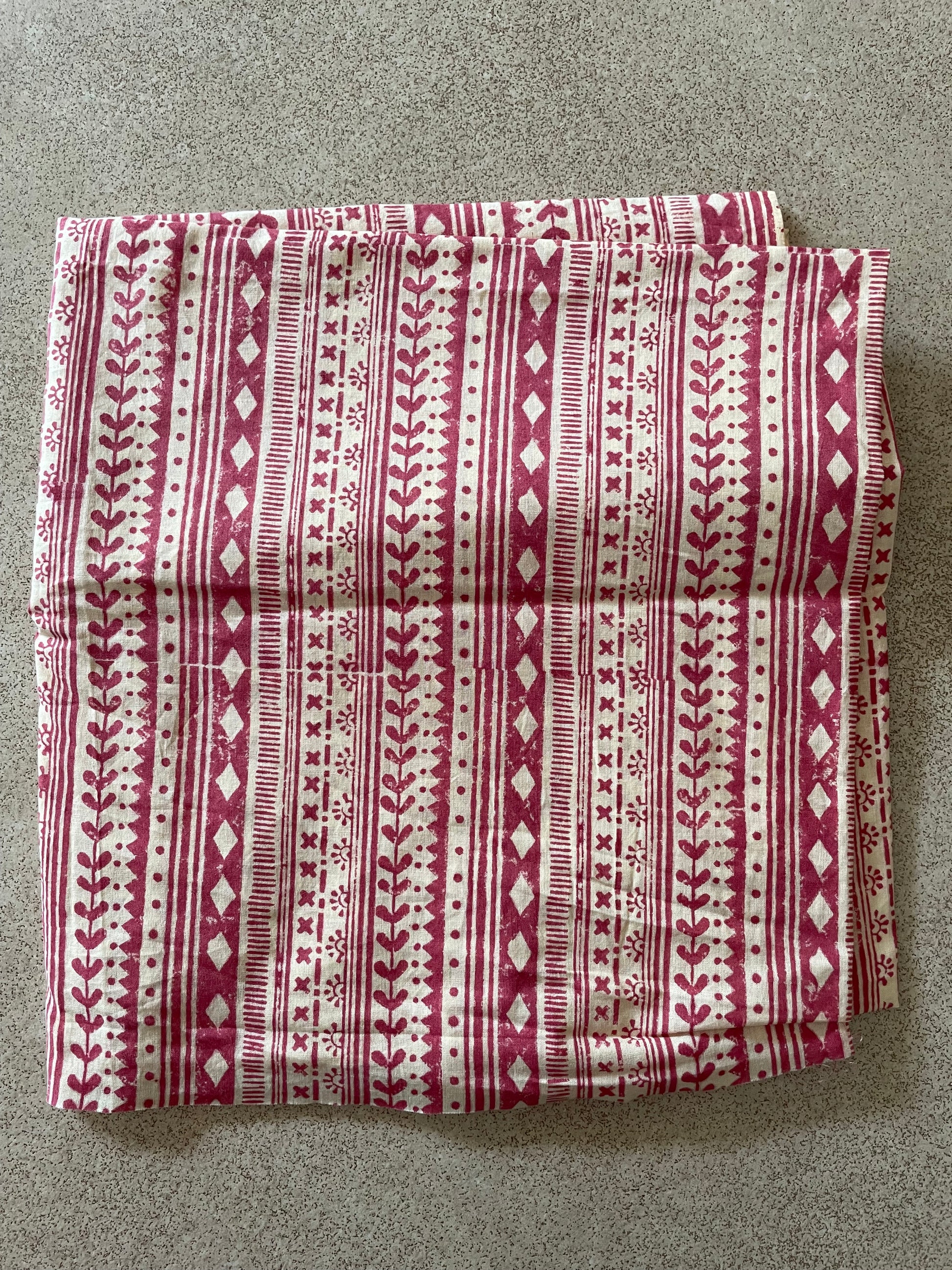 Folded Mogasu saree blouse piece with a red and cream pattern on a gray surface.
