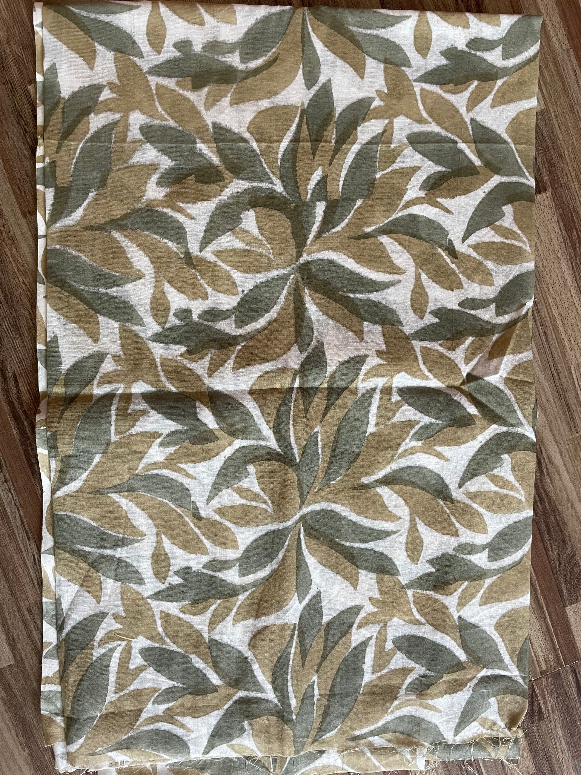 Folded Mogasu Tefal saree blouse piece with leaf pattern on a wooden surface.