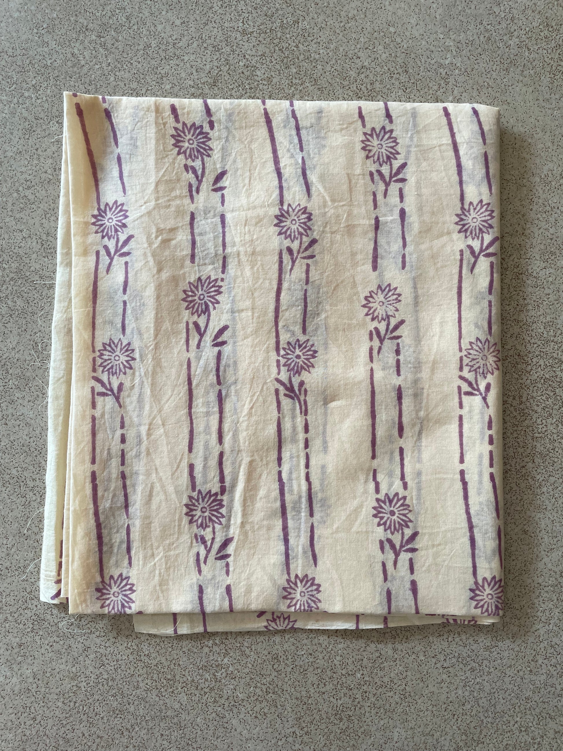 Folded Mogasu saree blouse piece with floral patterns on a gray surface