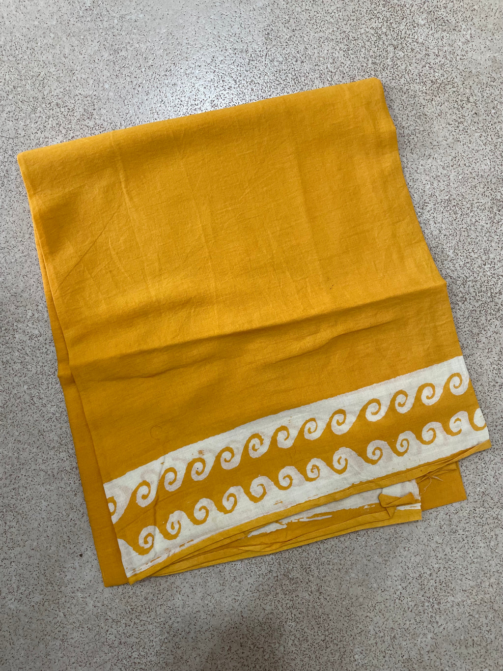 Yellow Mogasu Brisa saree blouse piece fabric with white decorative border on a gray surface