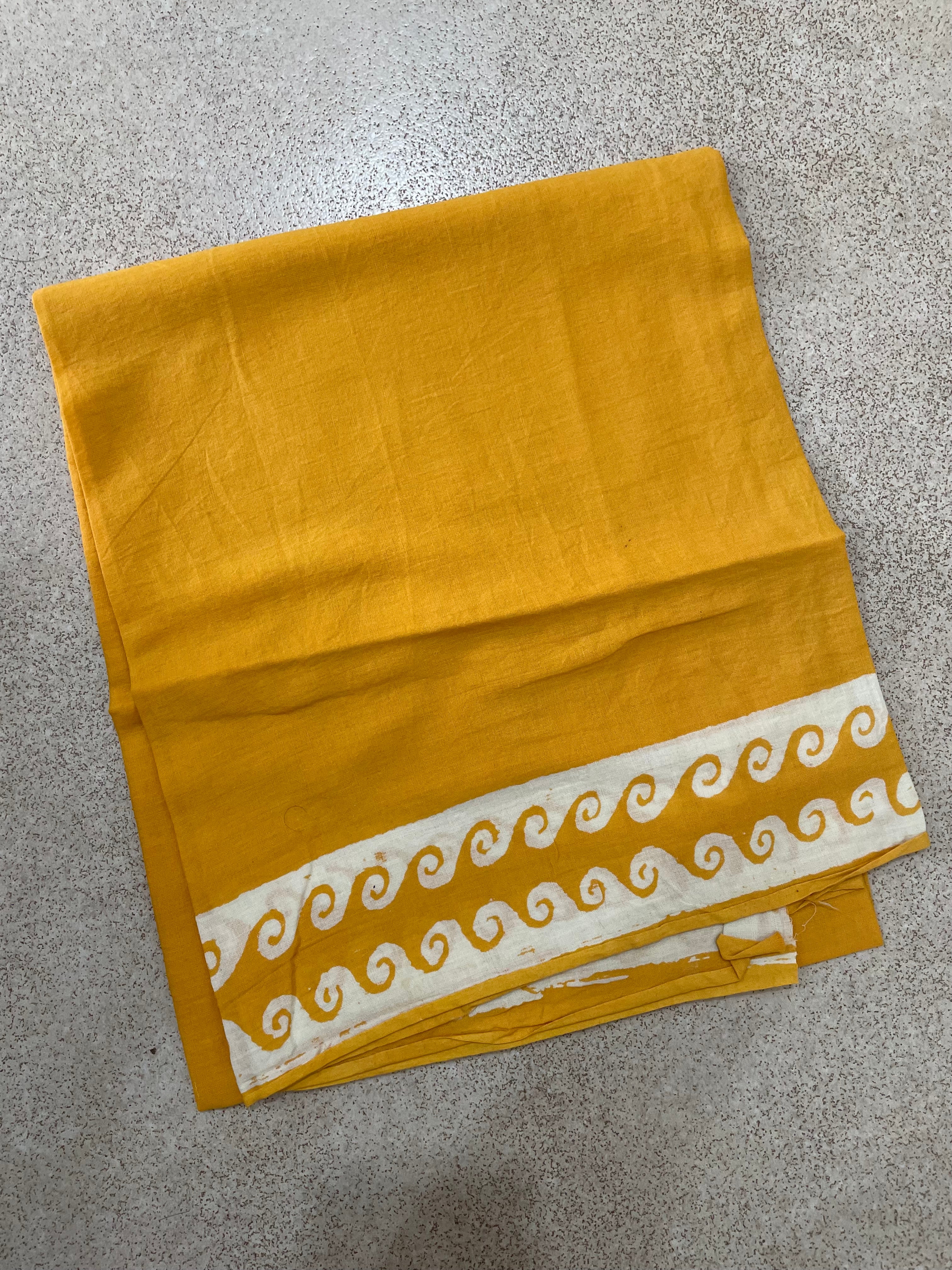Yellow Mogasu Brisa saree blouse piece fabric with white decorative border on a gray surface
