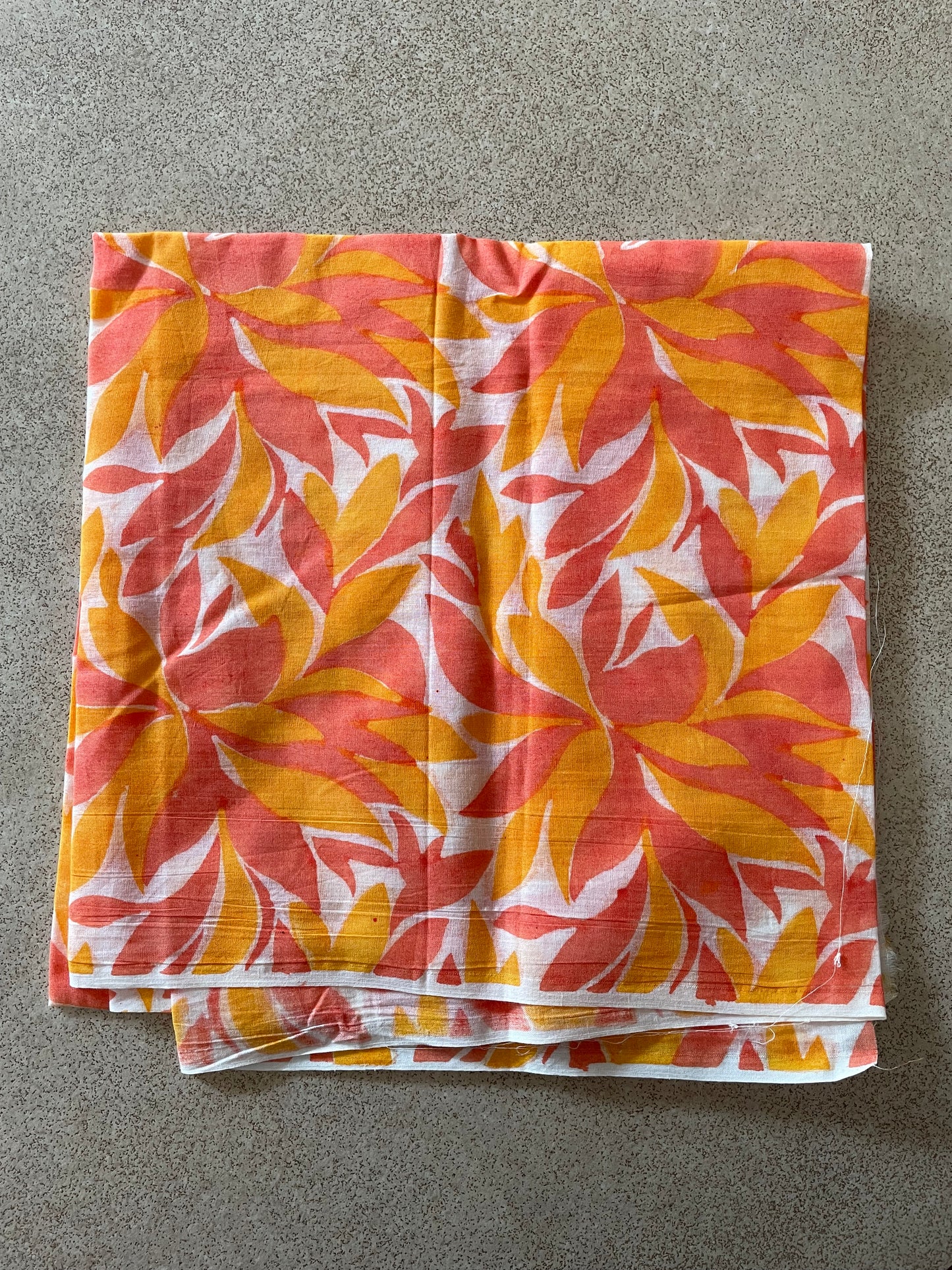 Folded Mogasu’s blouse piece with a floral pattern on a gray surface.