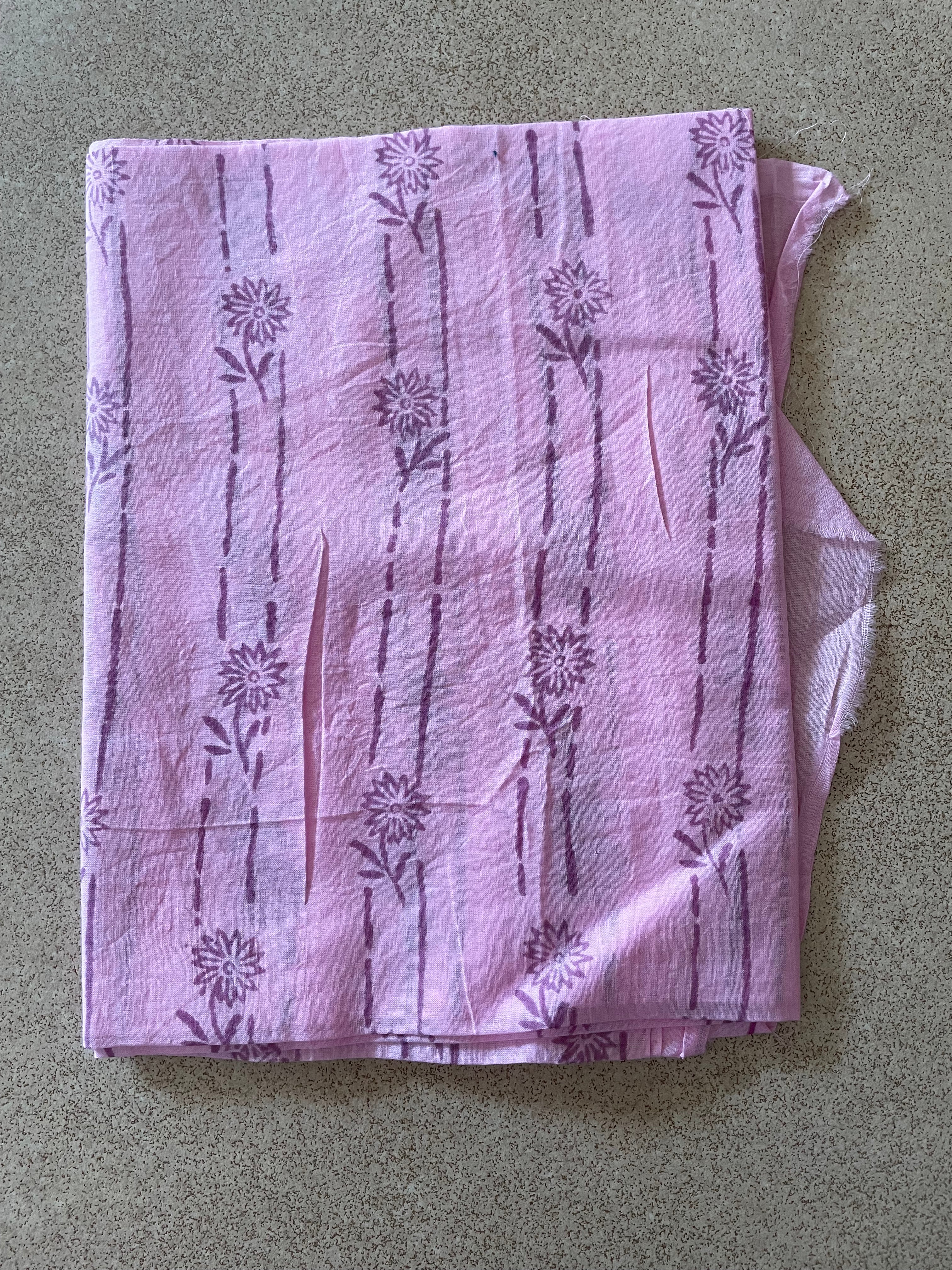 Folded Mogasu’s pink saree blouse piece with floral patterns on a beige surface