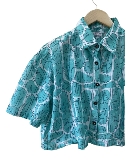 Teal patterned Mogasu shirt on a hanger against a white background