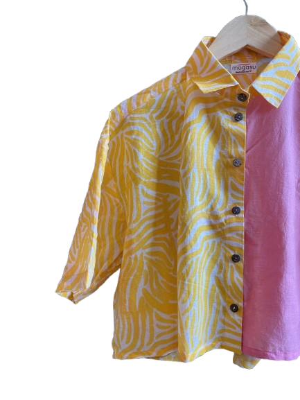 Yellow and pink patterned Mogasu shirt on a hanger with a white background
