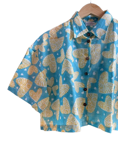 Blue Mogasu shirt with yellow butterfly pattern on a hanger