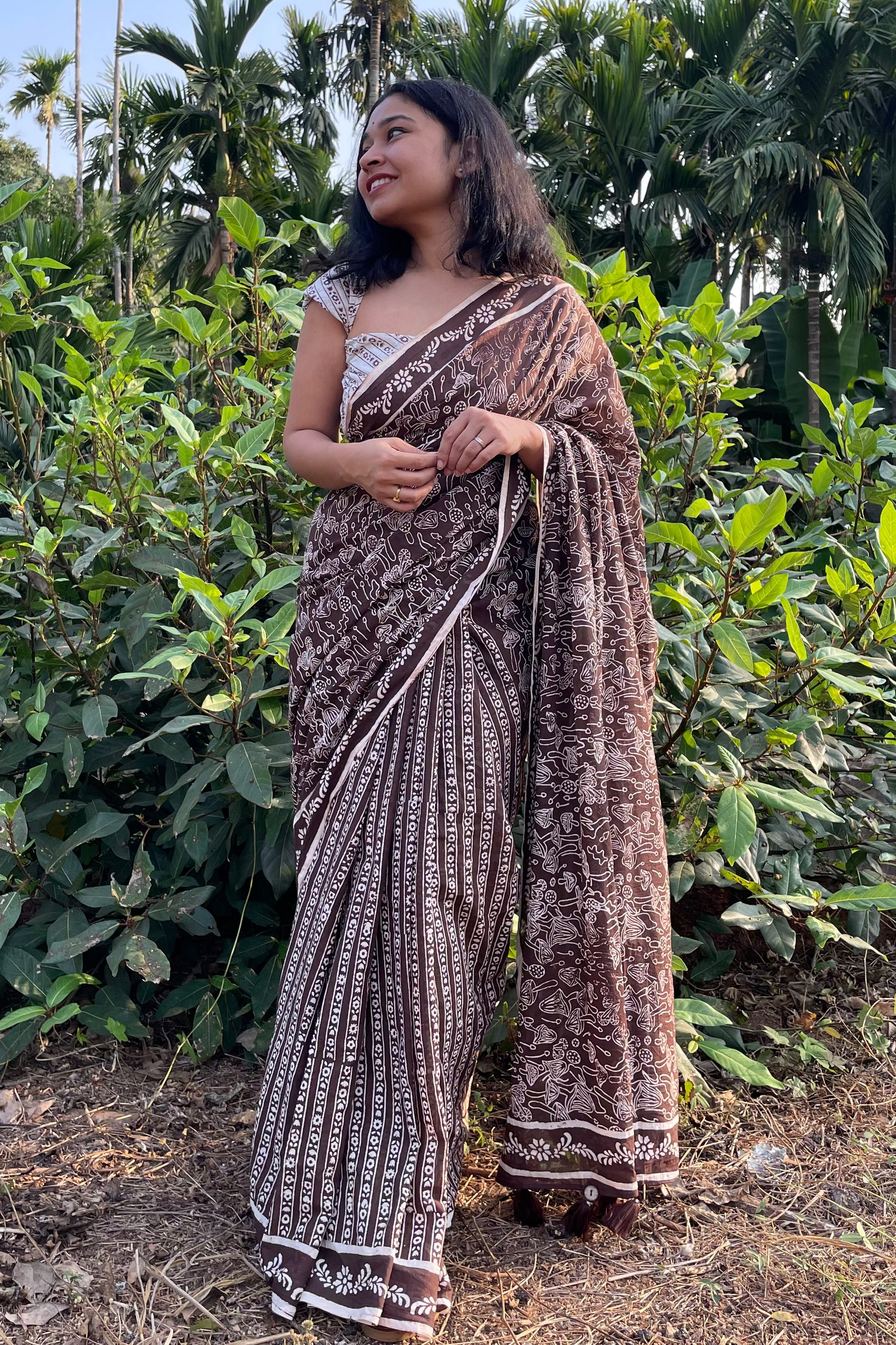Woman in a mushroom patterned saree from Mogasu standing in a natural setting with greenery in Goa. 