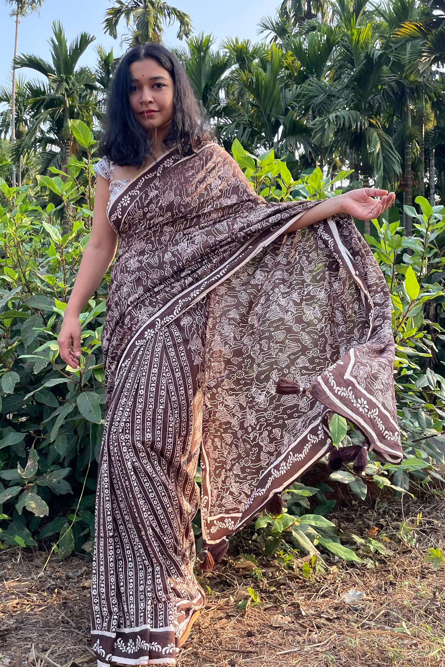 Woman in a Mushroom patterned mul cotton saree from Mogasu standing in a garden with greenery around in Goa