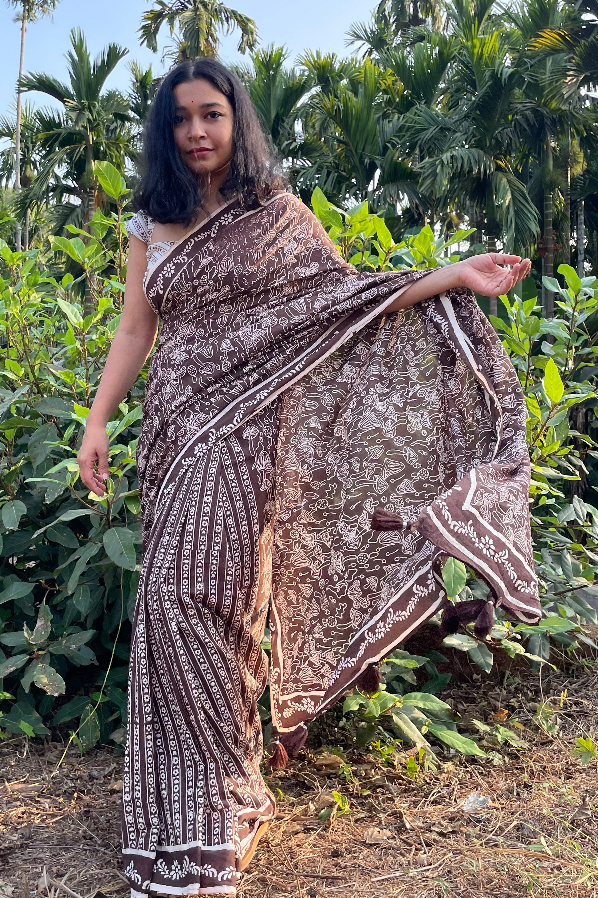 Woman in a Mushroom patterned mul cotton saree from Mogasu standing in a garden with greenery around in Goa