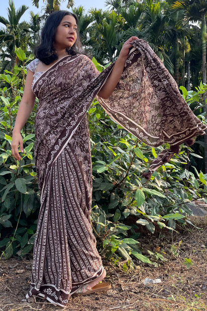Woman in a mushroom patterned Mogasu mul cotton saree standing outdoors with greenery in Goa.
