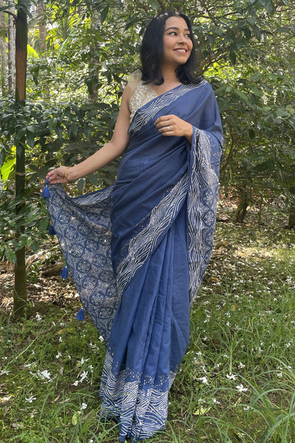Woman in a blue Mogasu saree with white wave patterns standing in a Goan spice plantation setting