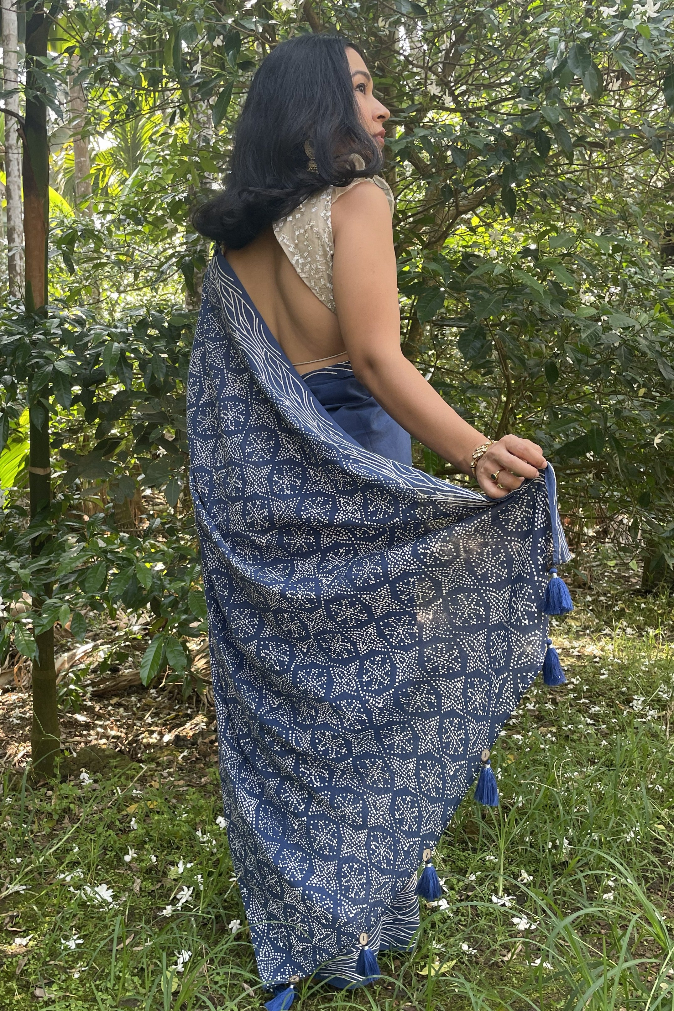 Woman wearing a Mogasu’s blue Starry Surf waves patterned saree with tassels in a forest setting in Goa