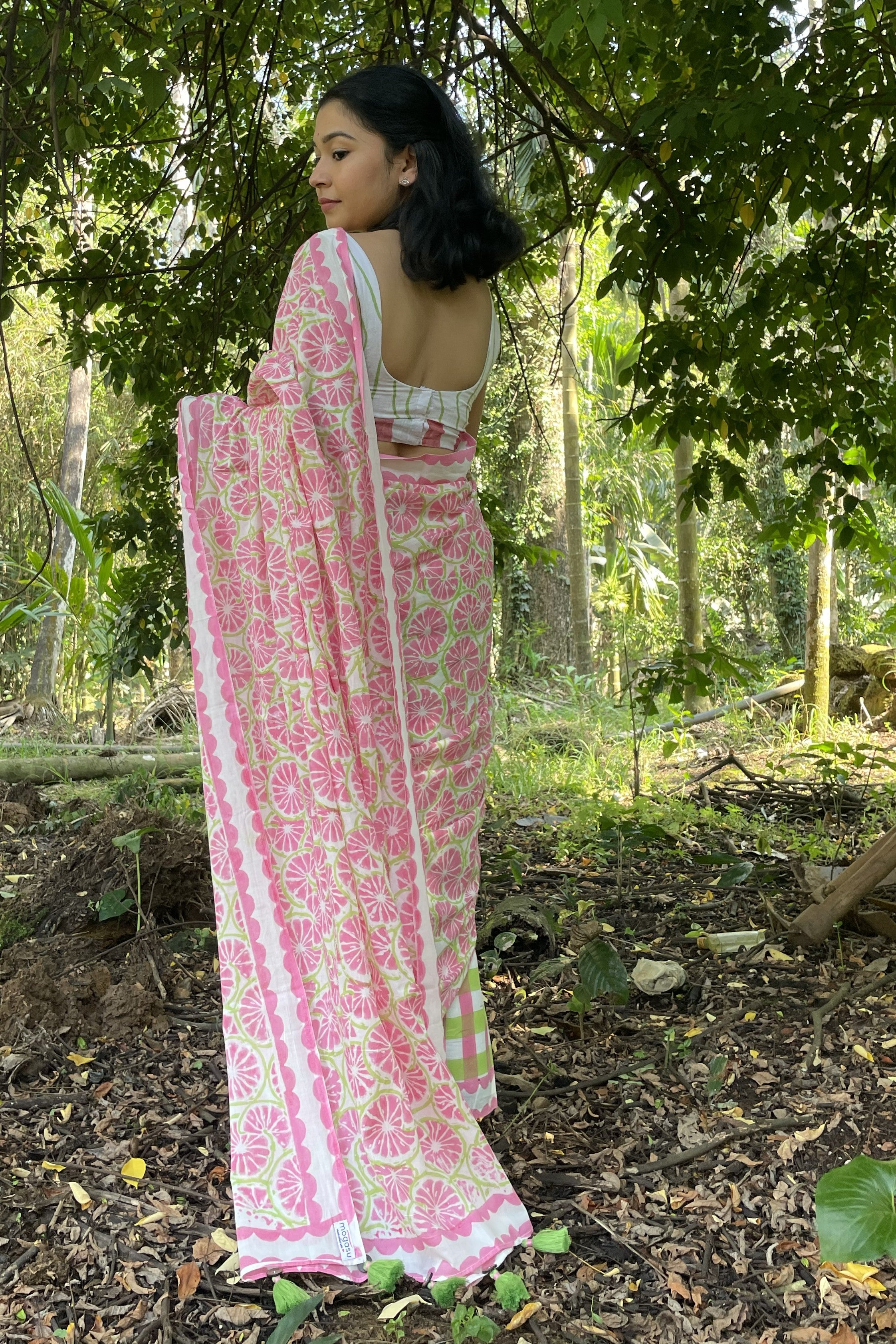 Woman in a Mogasu pink and white mul cotton saree standing in a forest in Goa setting