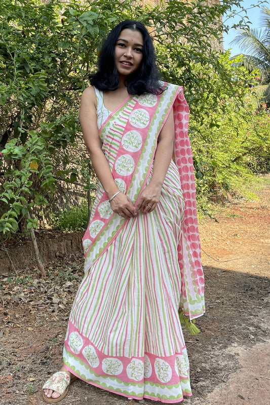 Woman in a Mogasu pink and white mul cotton saree standing outdoors with greenery in the background in Goa