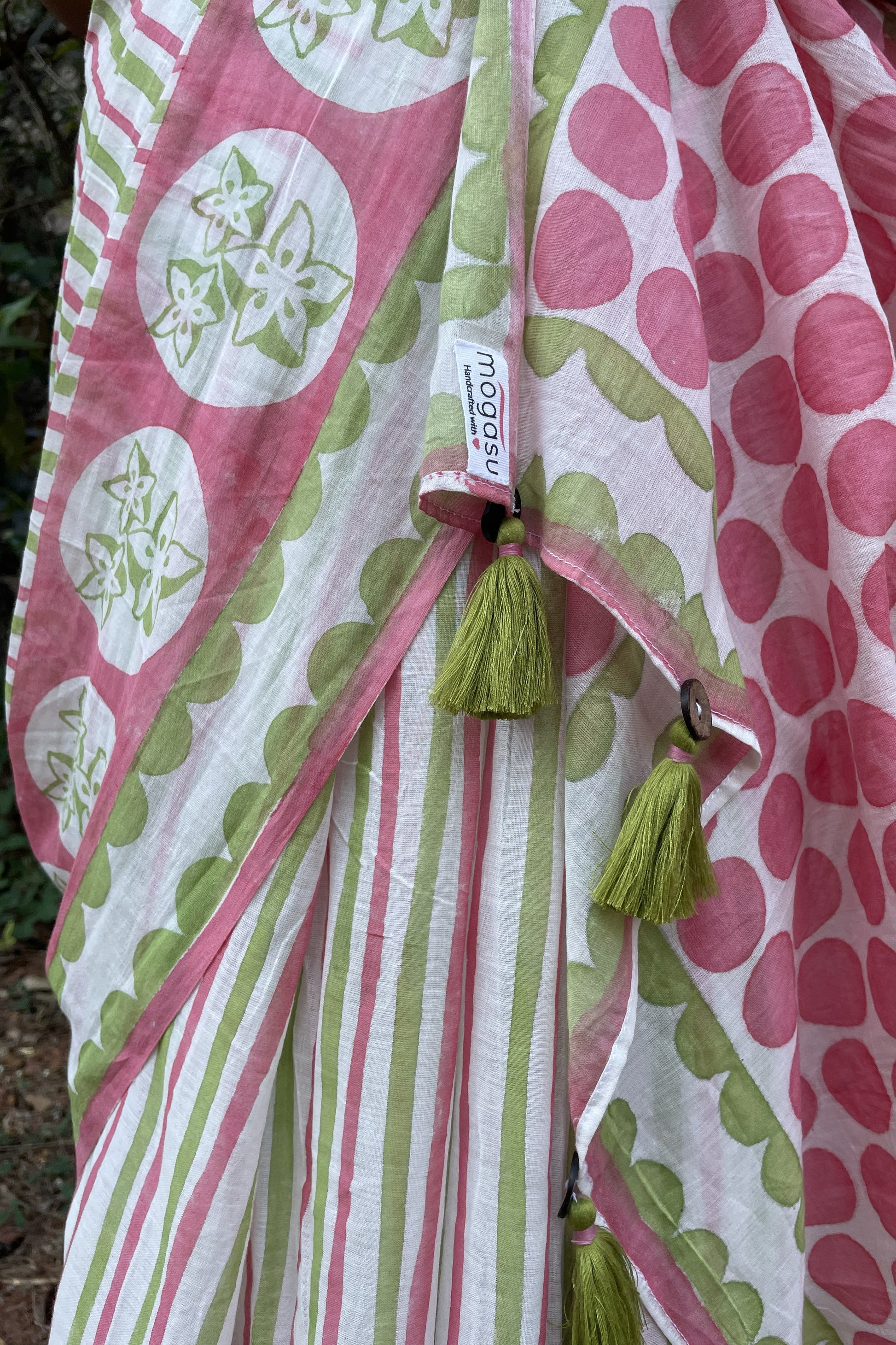 Pink and green patterned saree close up with tassels and a visible Mogasu brand tag.