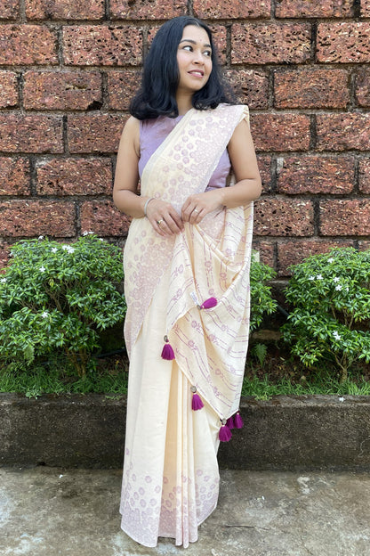 Woman in a Mogasu cream saree with pink blouse standing against a brick wall in Goa.