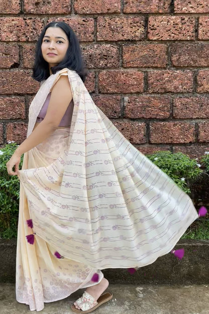 Woman wearing a Mogasu cream saree with a brick wall background