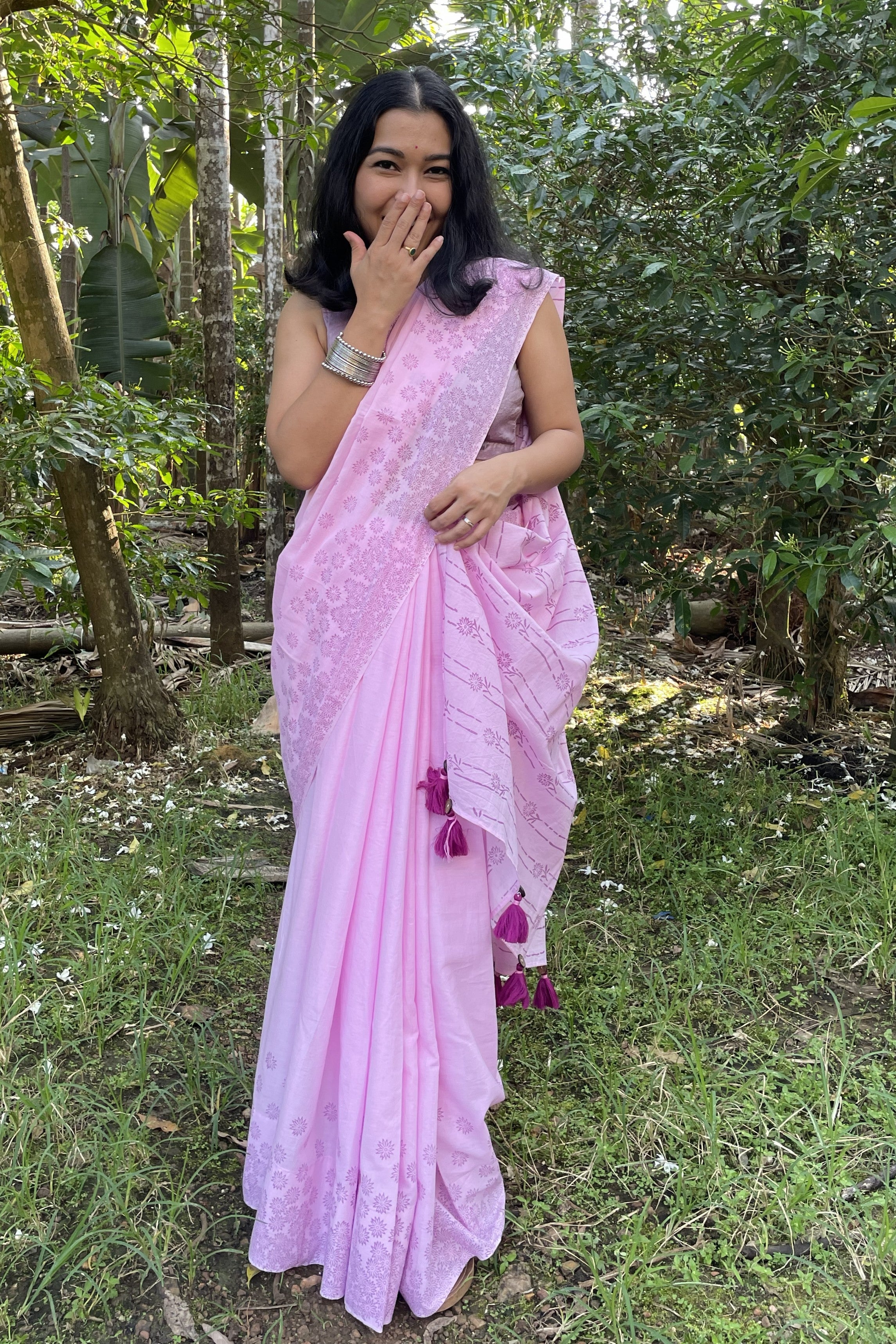 Woman in a Mogasu pink mul cotton saree standing in a forested area in Goa