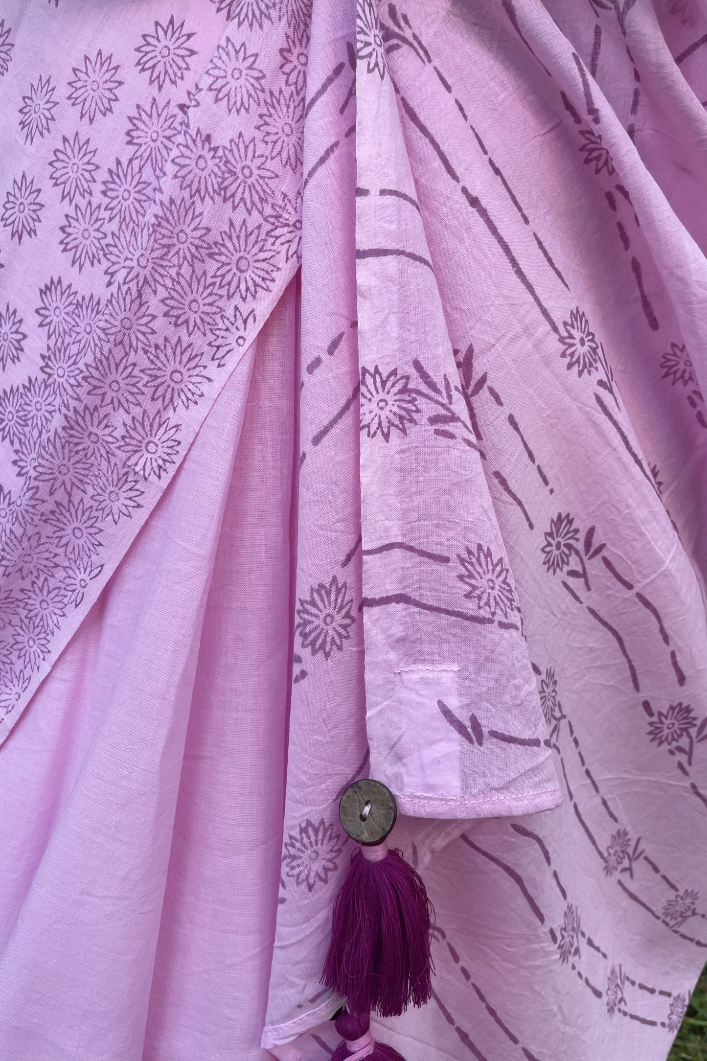 Close-up of a Mogasu pink saree with floral patterns and a button with tassels at pallu.
