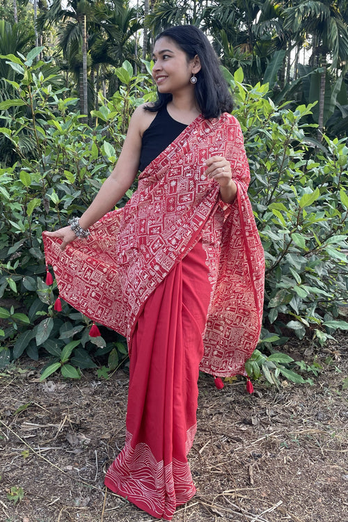 Woman wearing a red mul cotton Mogasu saree with a patterned border in a natural setting in Goa