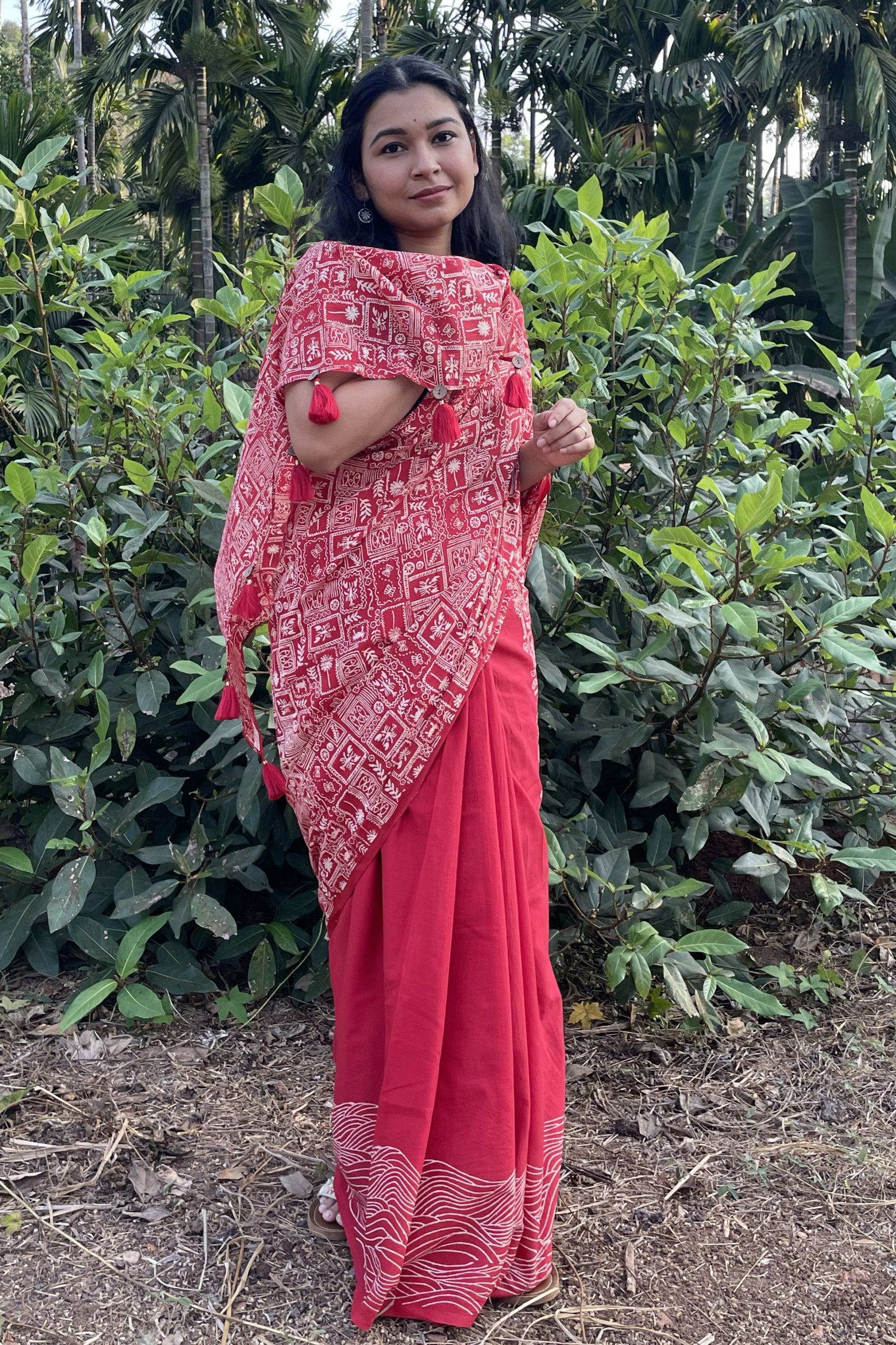 Woman wearing a Mogasu red saree with a patterned blouse in a forest setting in Goa.