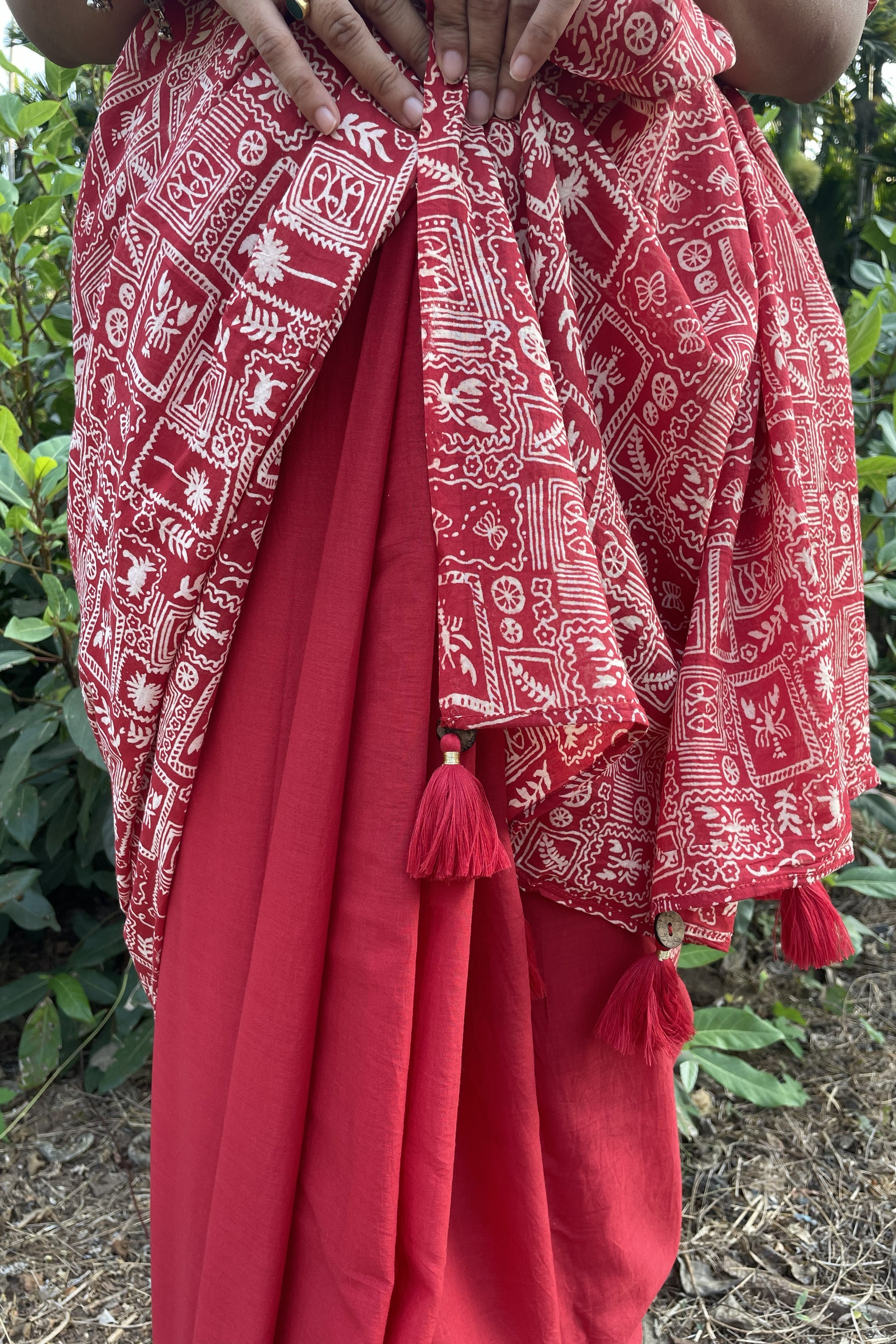 Red Mogasu mul cotton saree with white patterns held by a person against a natural background in Goa