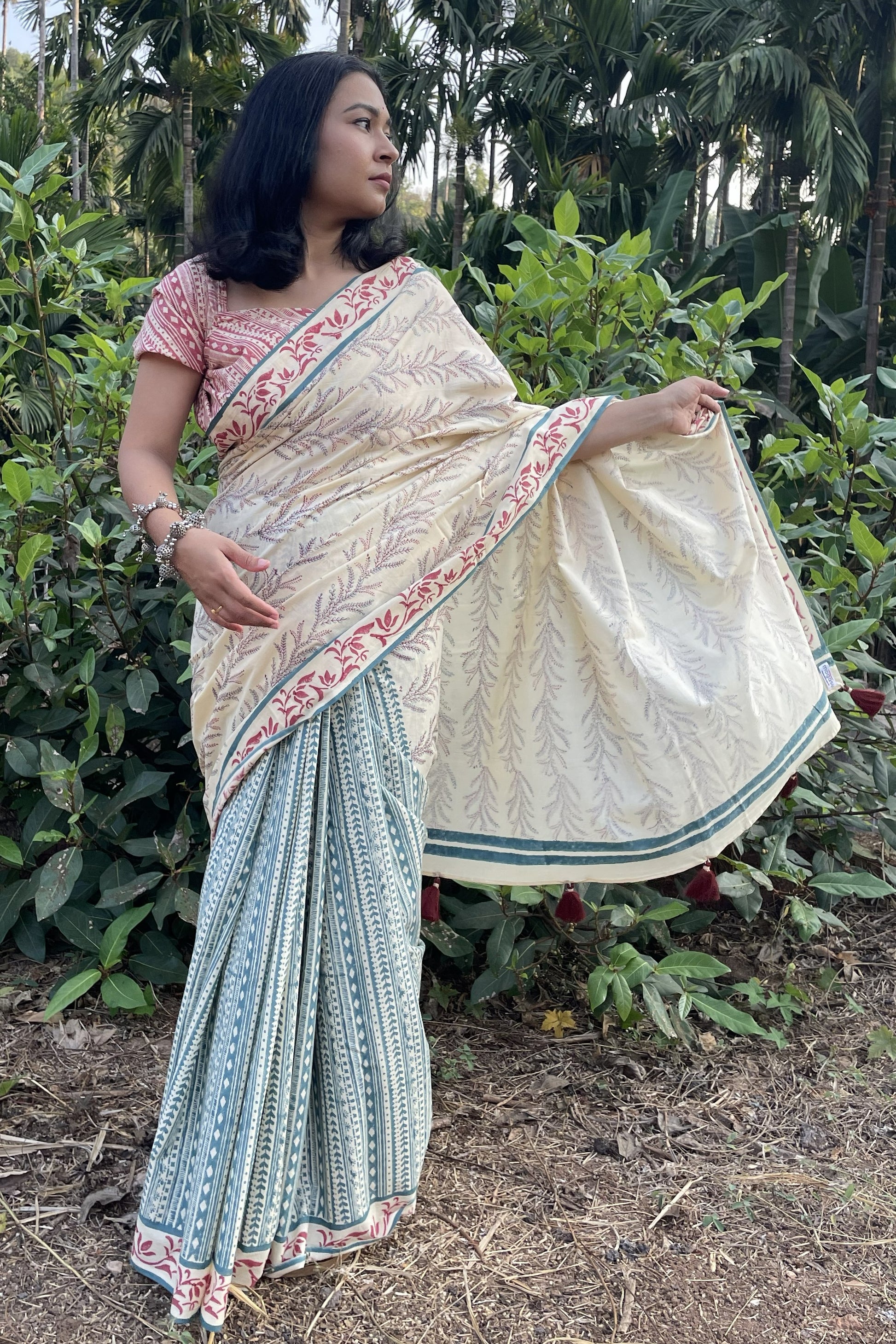 Woman wearing a Mogasu mul cotton saree in a natural setting with greenery.
