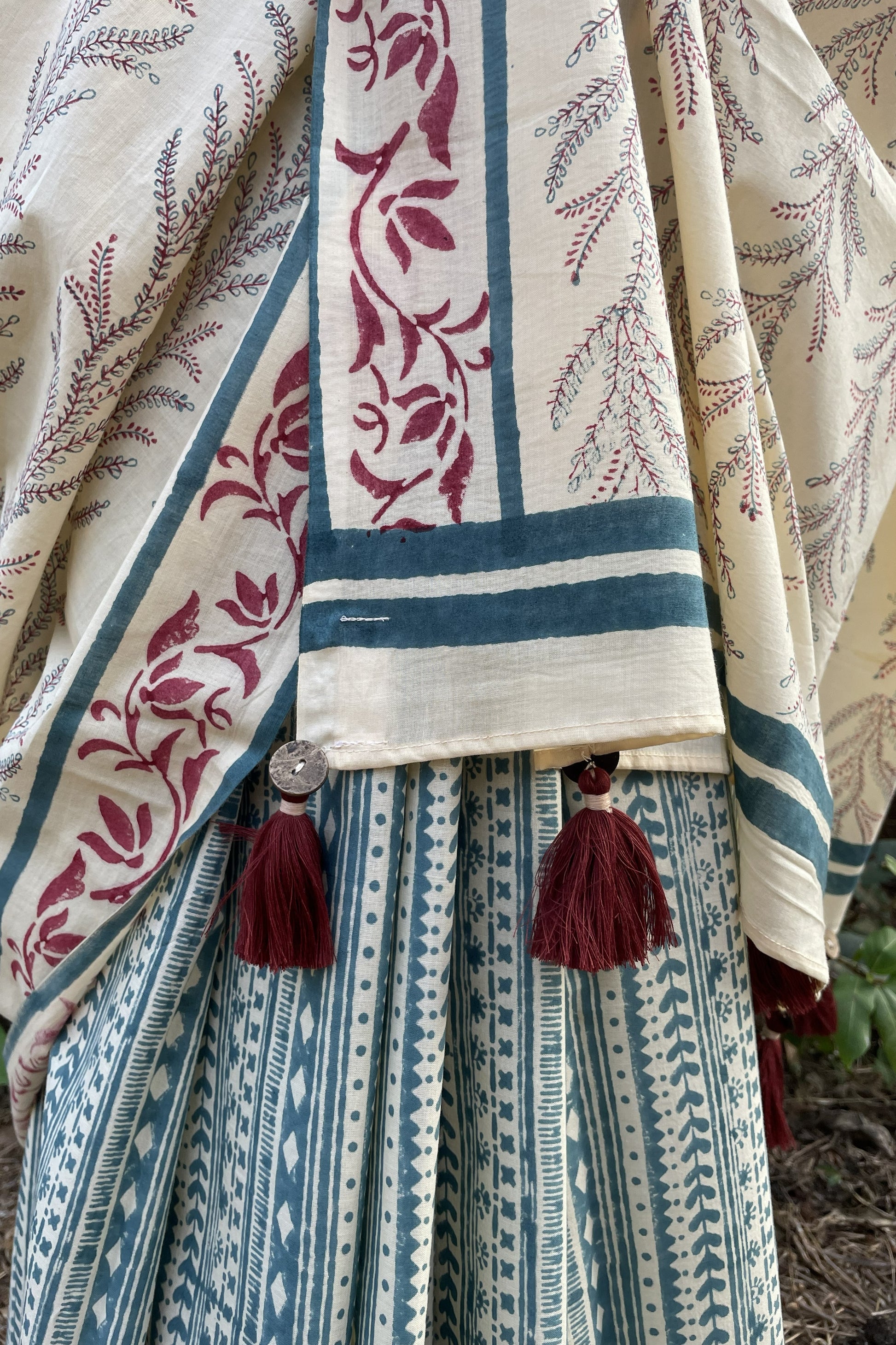 Mogasu mul cotton saree with geometric intricate patterns and tassels on a neutral background.