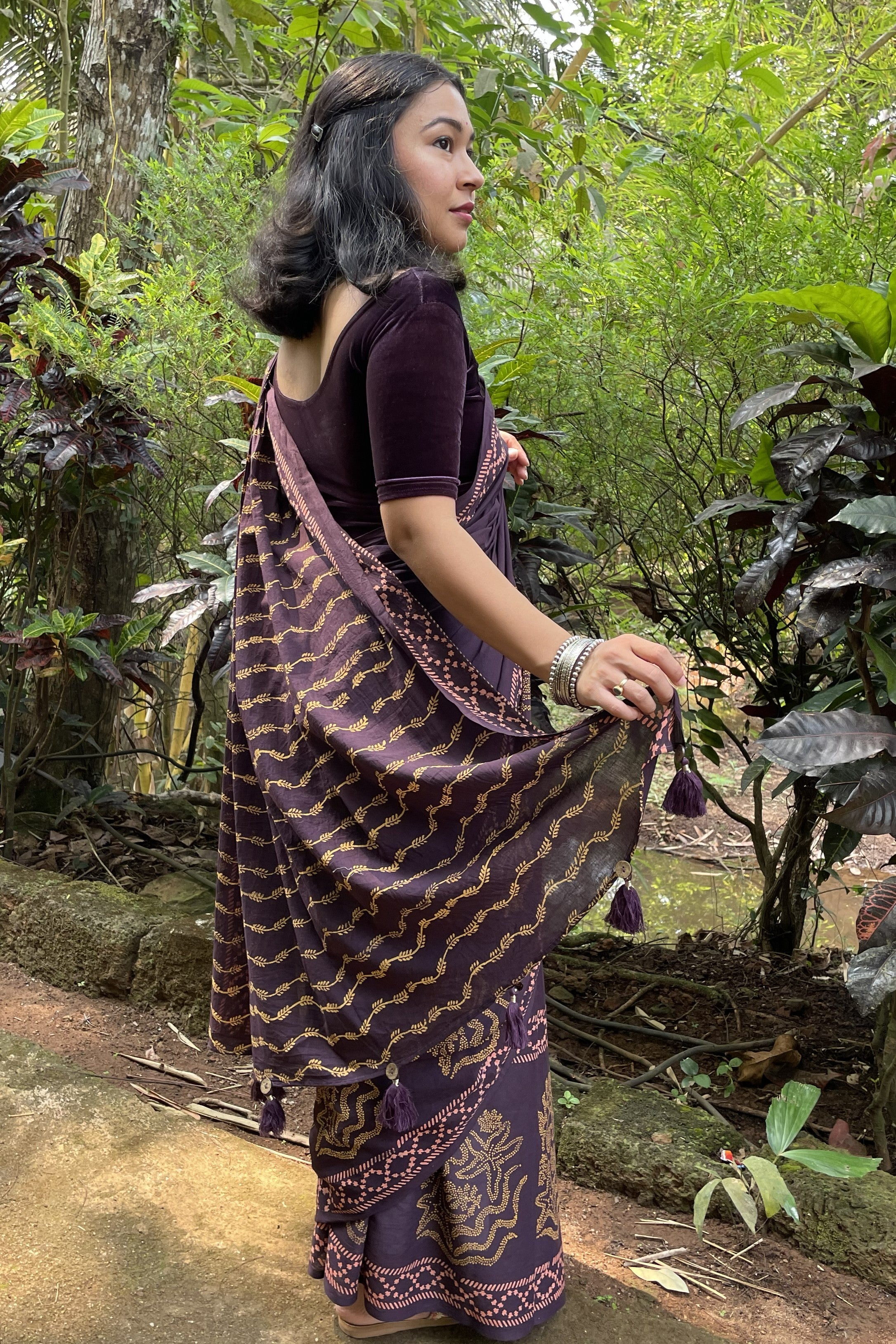 Woman in a patterned purple Mogasu saree standing in a forest n Goa