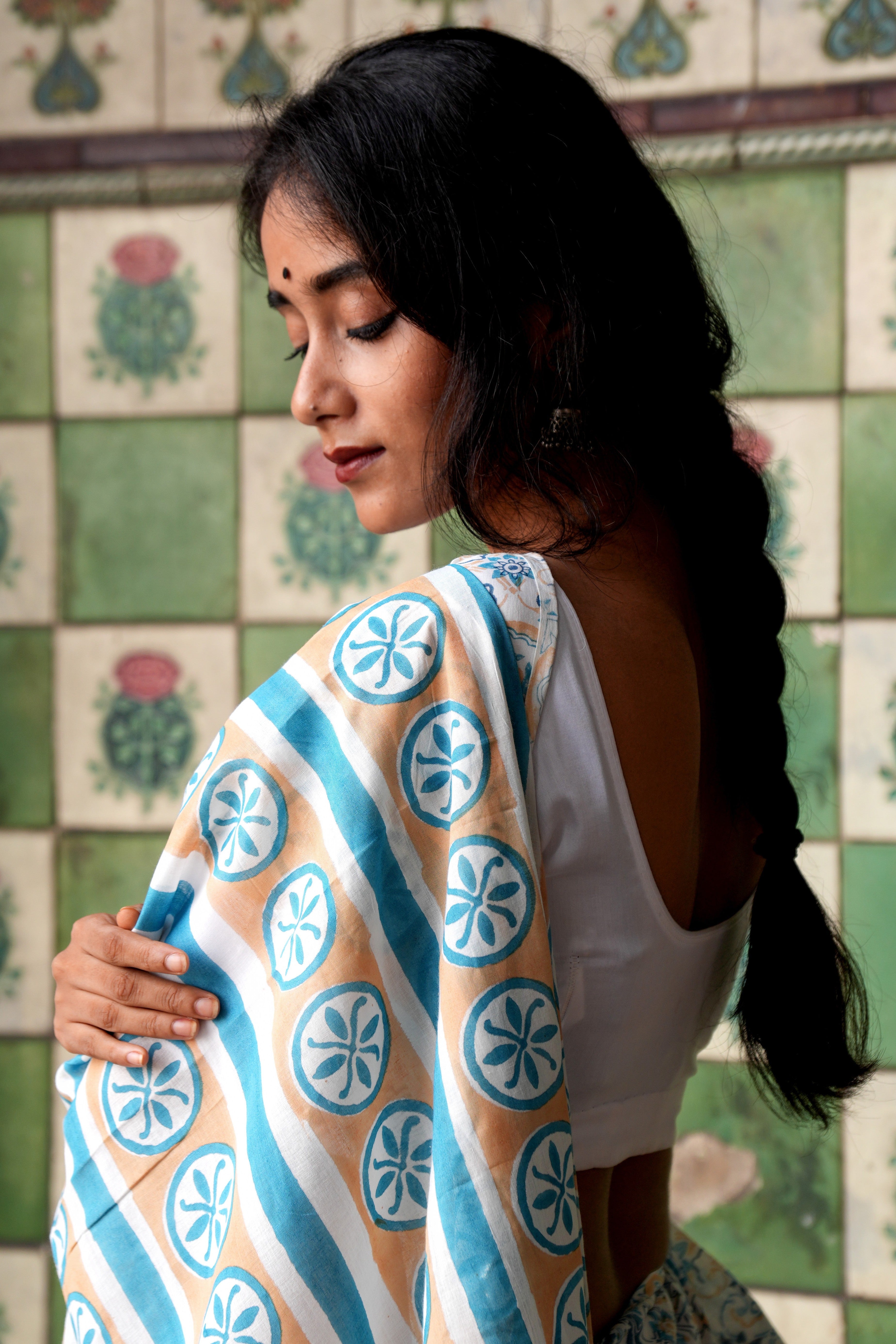 Woman holding a Goan Azulejo patterned saree against a tiled wall