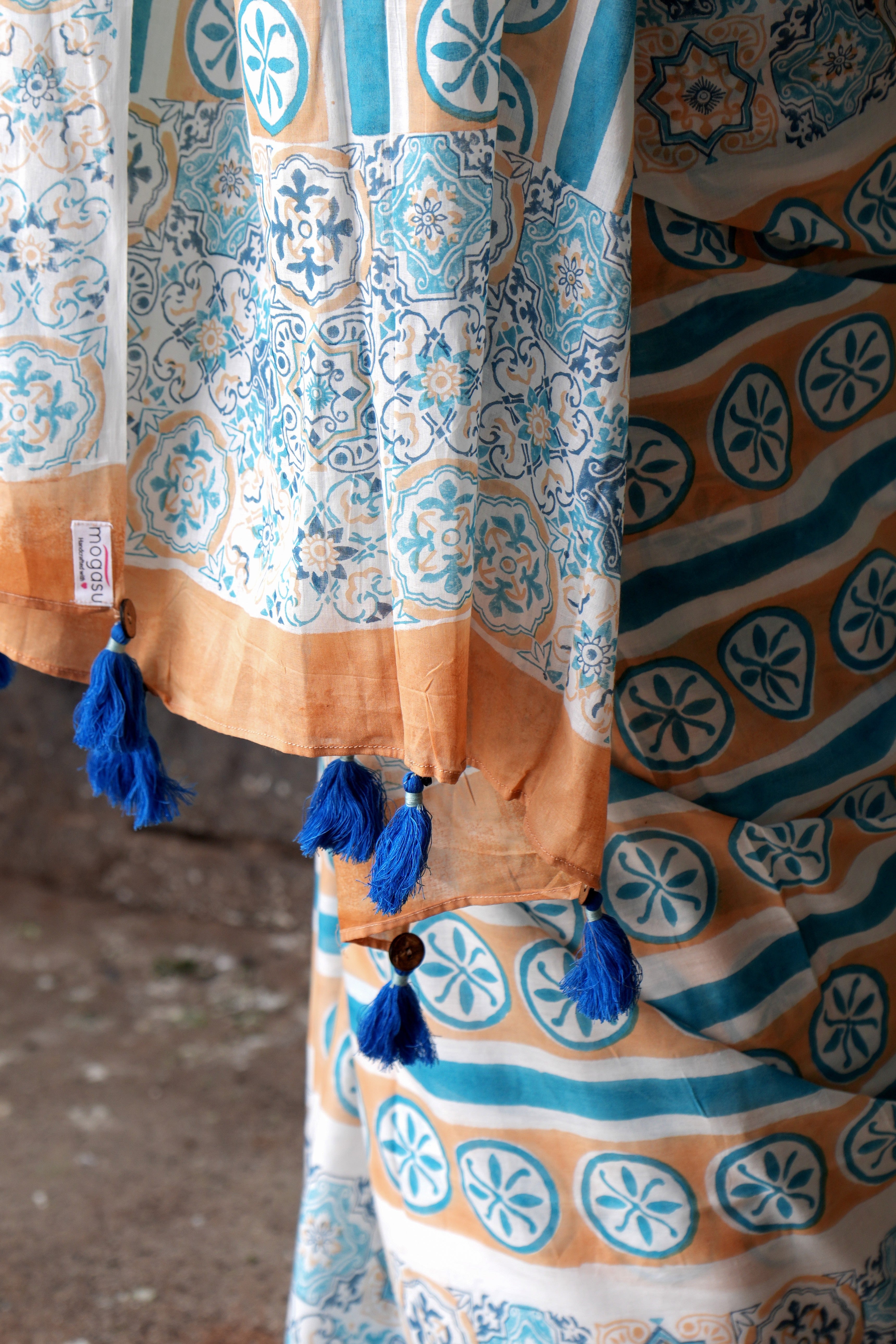 Colorful Goan Azulejo saree fabric with patterns and tassels on a textured surface