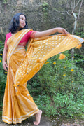Woman in a yellow Mogasu saree with white patterns standing outdoors against a natural background in Goa
