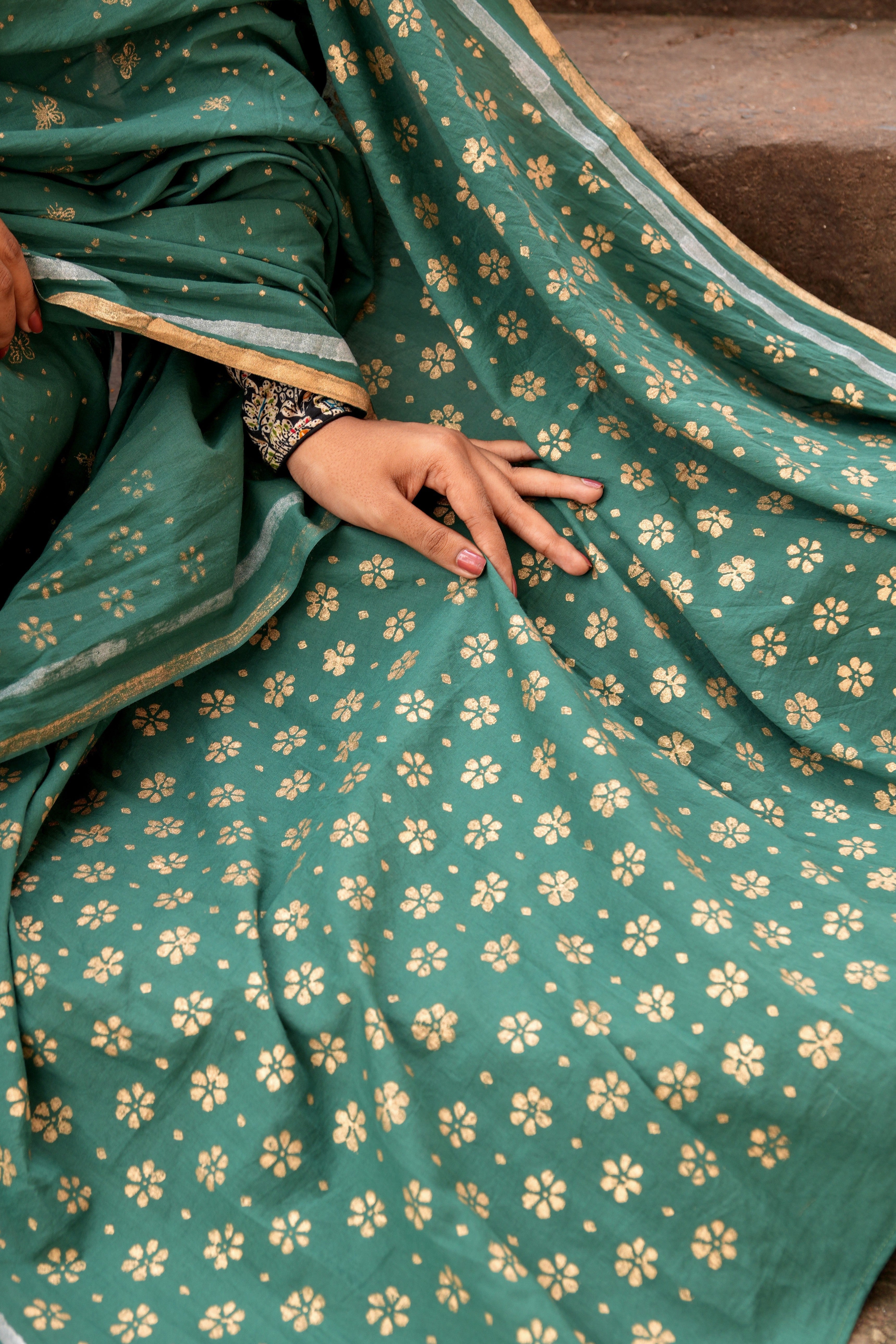 Green Mogasu saree with gold floral pattern held by a person