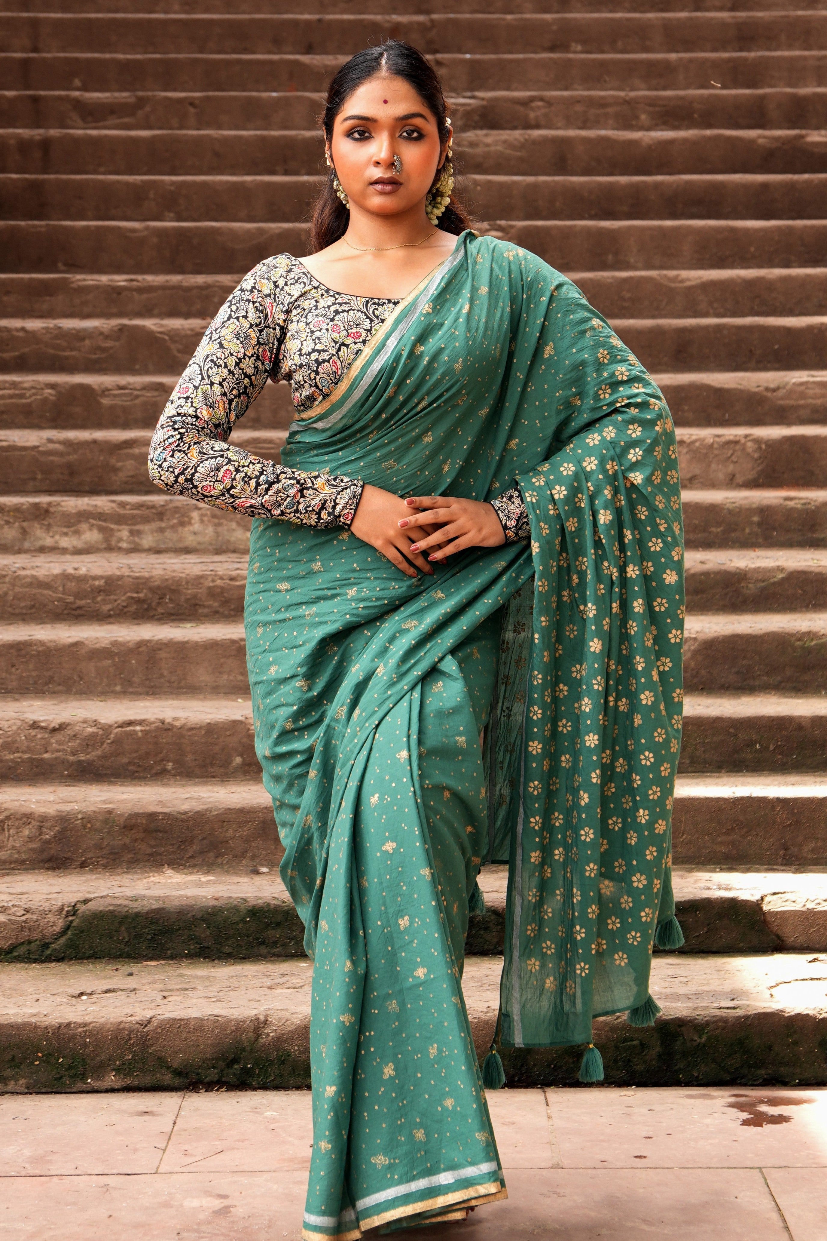 Woman in a green Mogasu Cazulo saree standing on stone steps