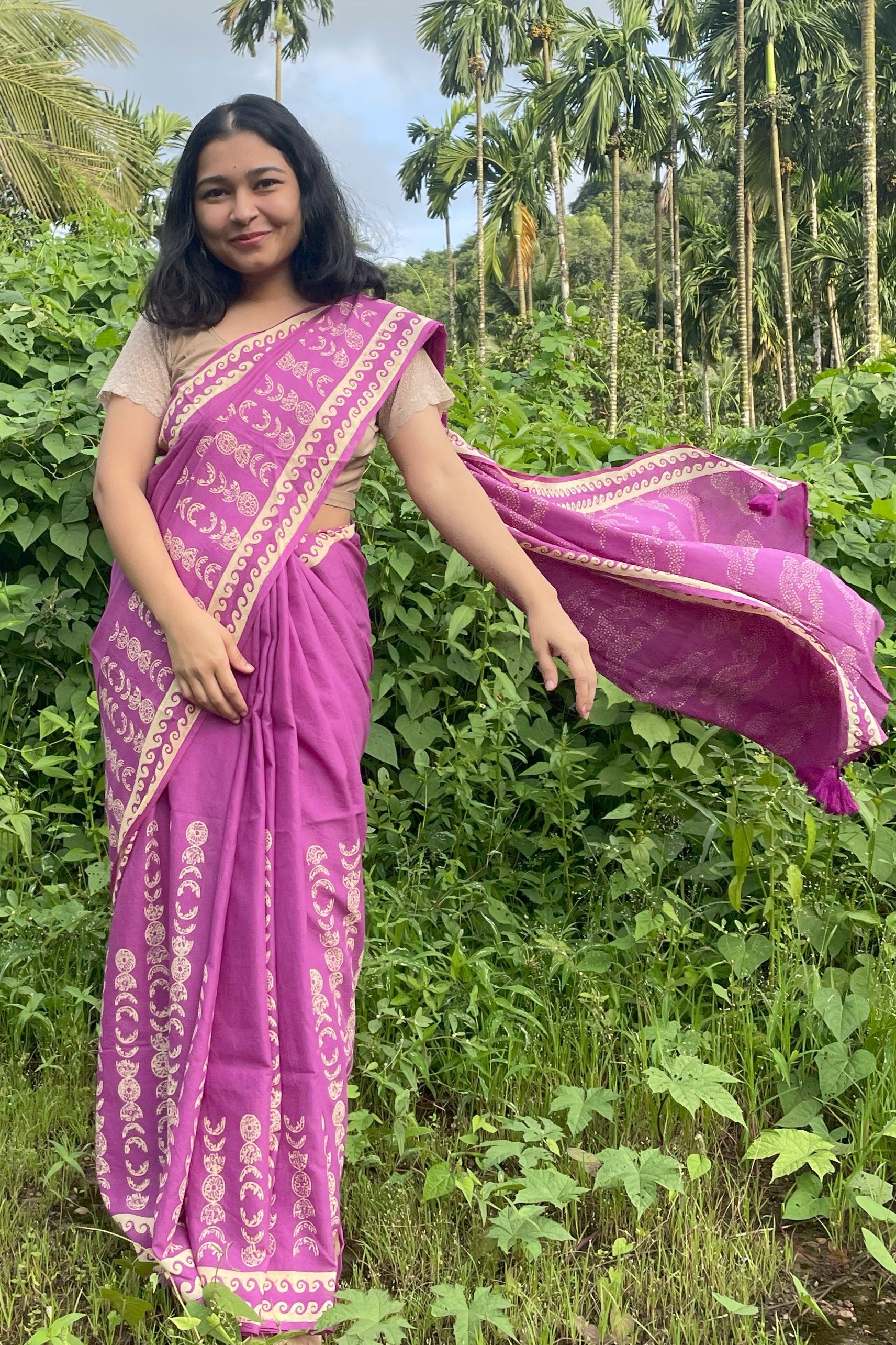 Woman in a purple Mogasu mul cotton saree with a green forest background in Goa
