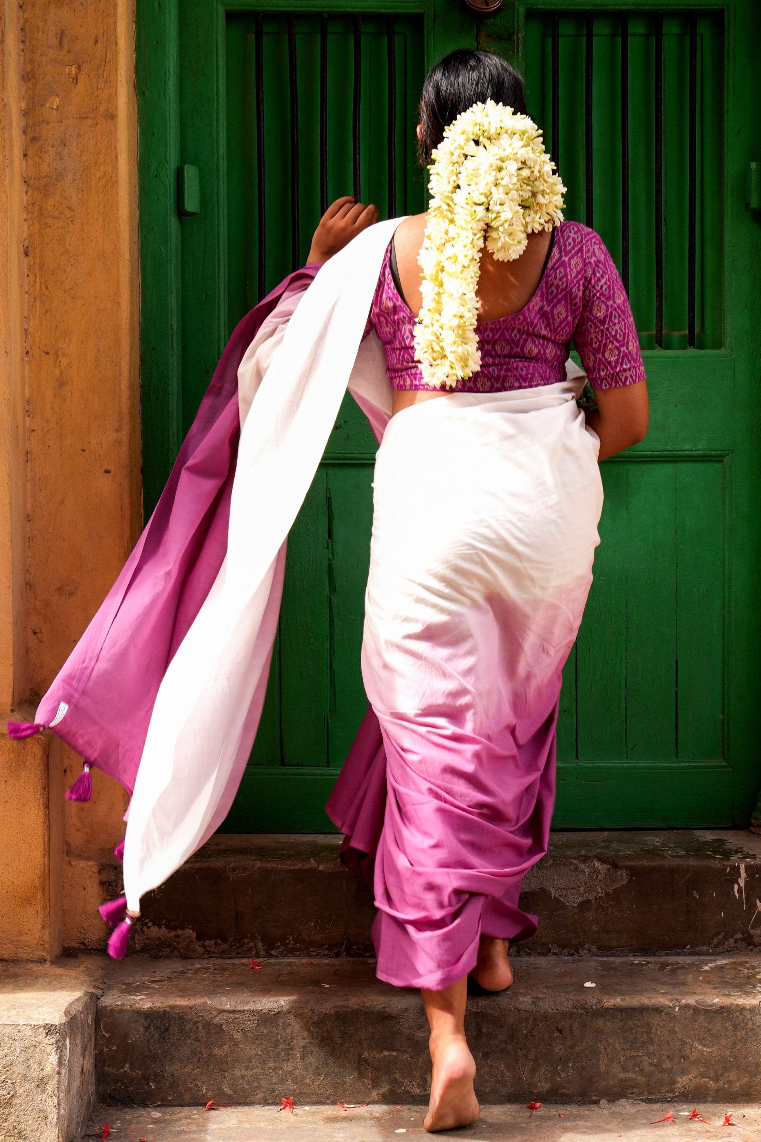 Woman in traditional Indian Mogasu saree attire walking up steps with a green door in the background