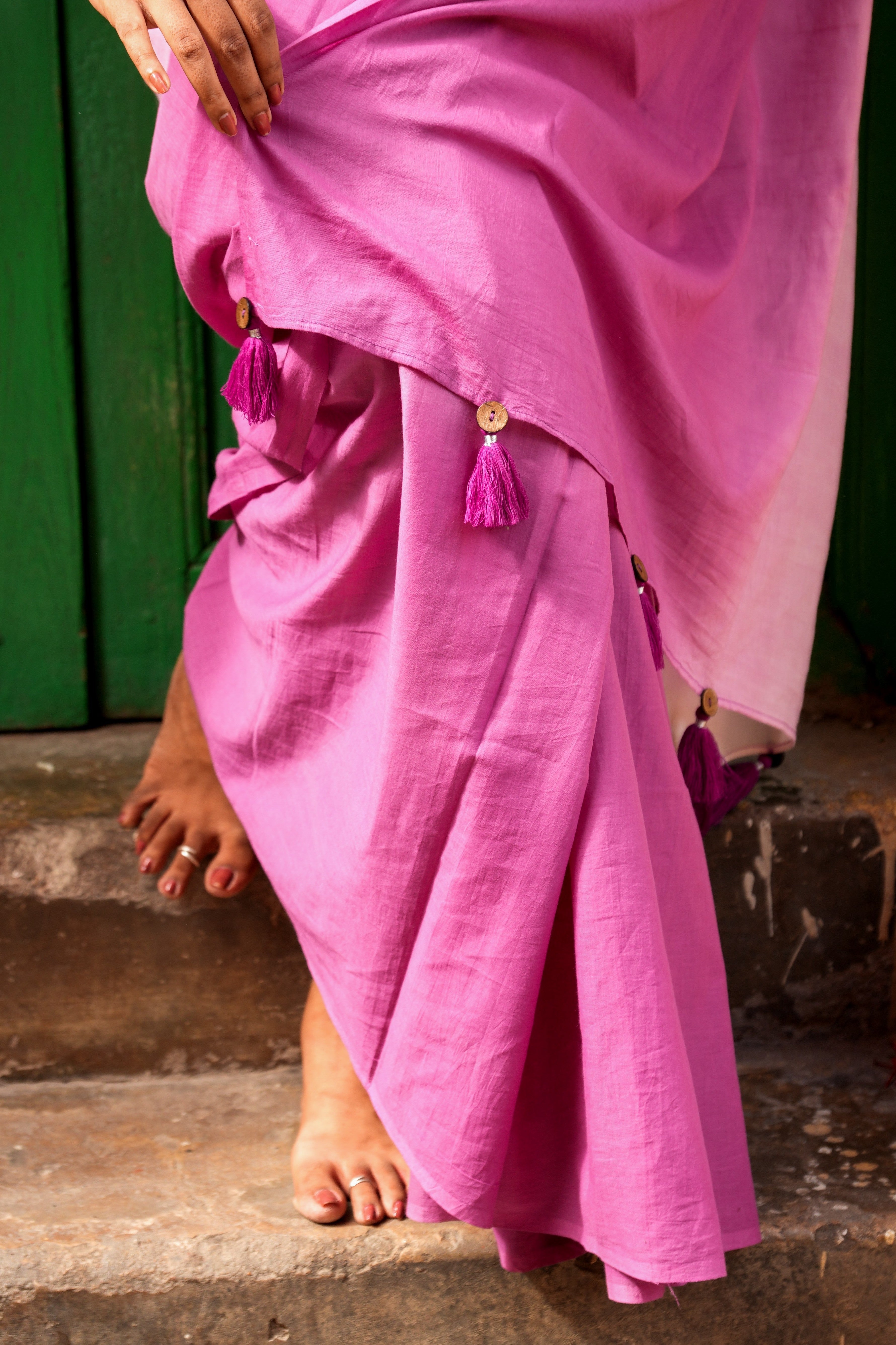 Person wearing a pink Mogasu saree with a green background